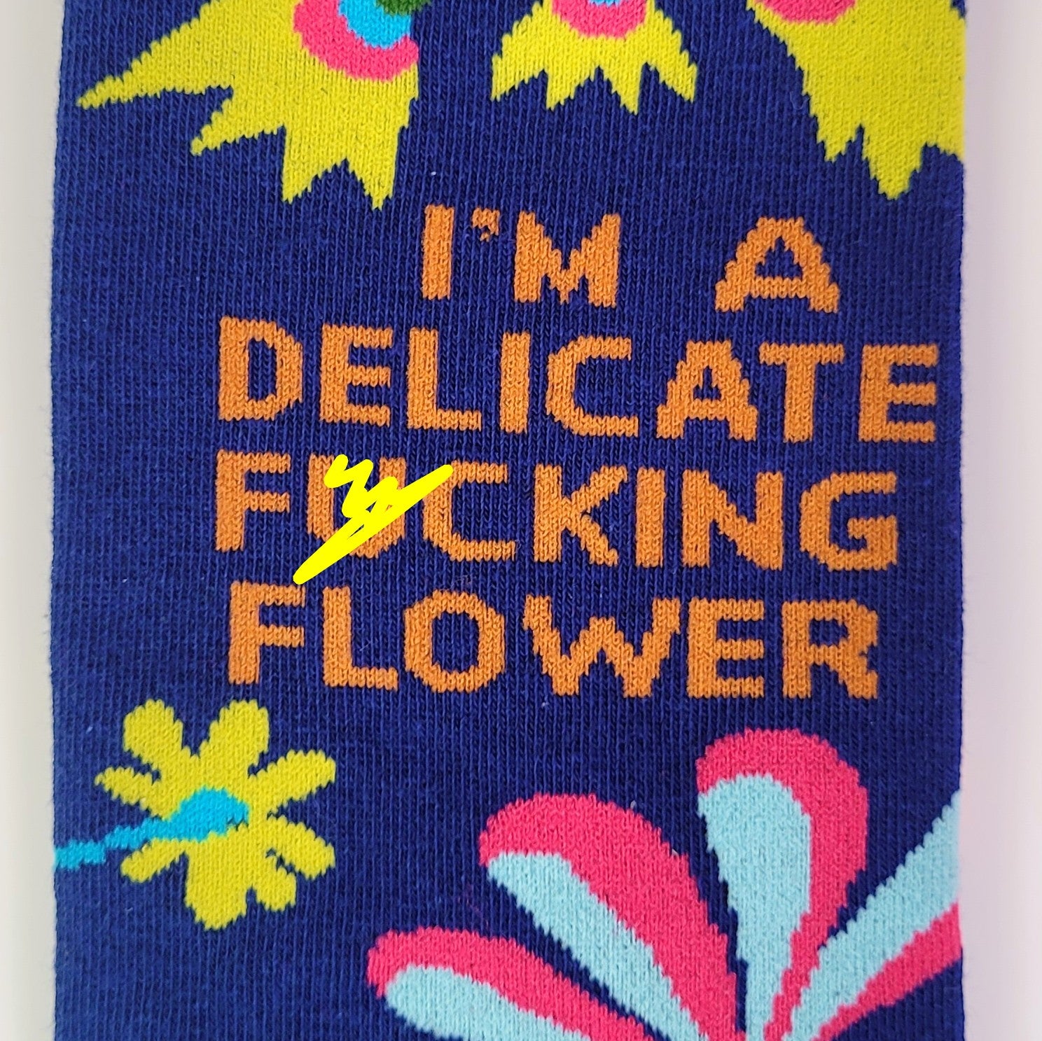 Sock with floral design and text 'I'm a delicate fucking flower' on a blue background