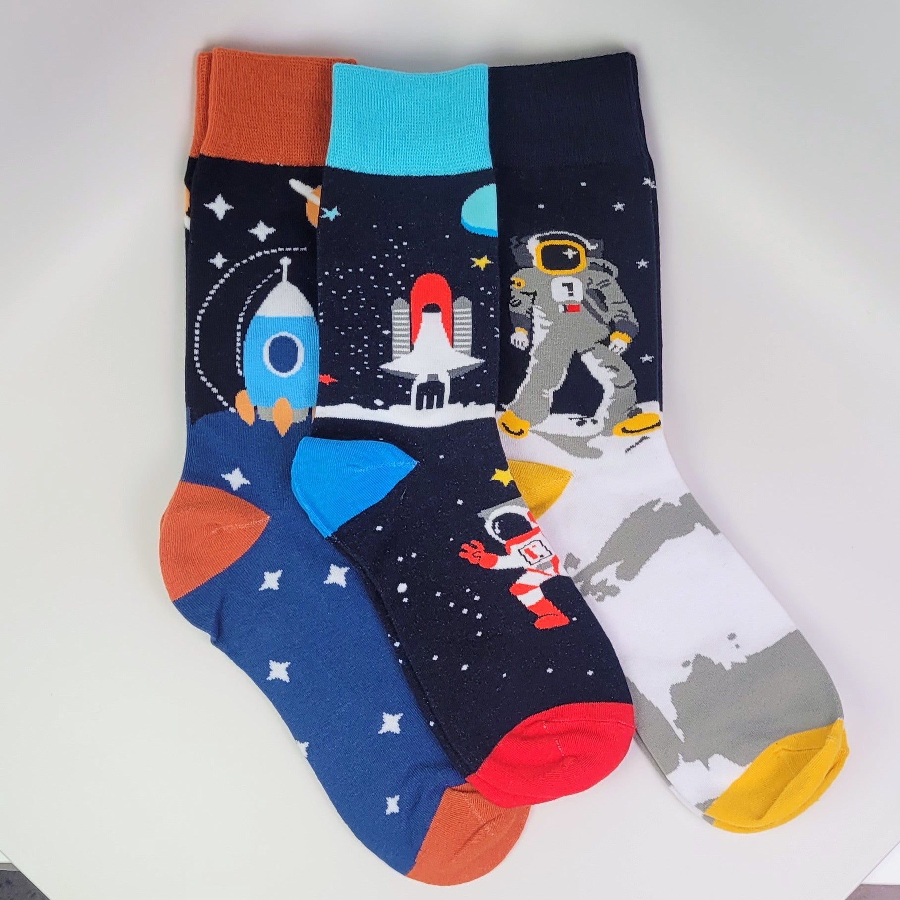Three pairs of socks with space-themed designs on a white background