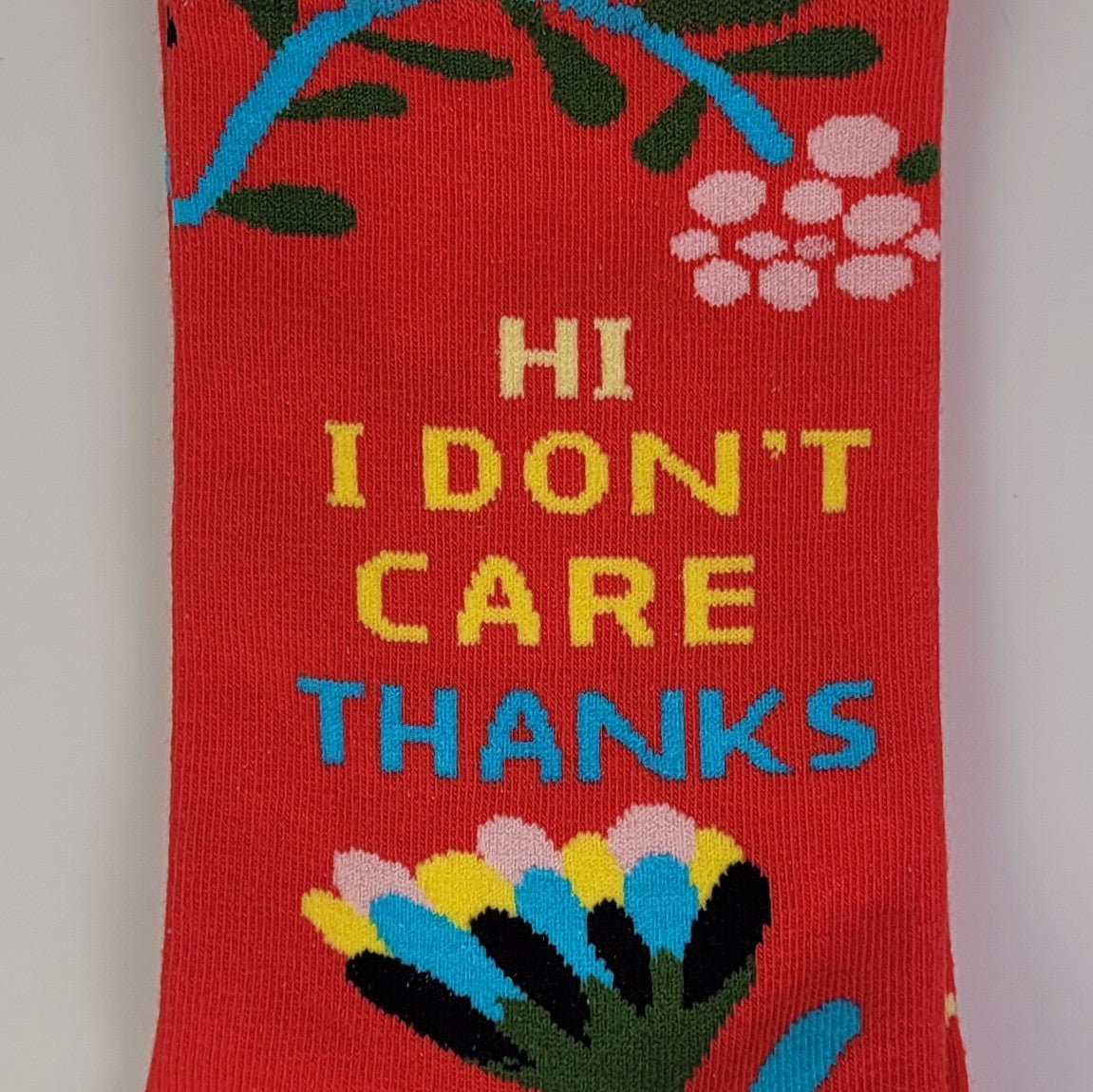Red sock with floral designs and text 'HI I DON'T CARE THANKS' on a plain background